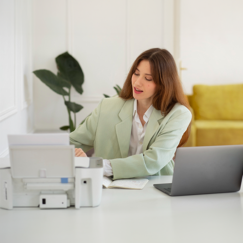 A Woman Sitting at a Chair with a Laptop and Printer, Exploring Check Printing Programs.