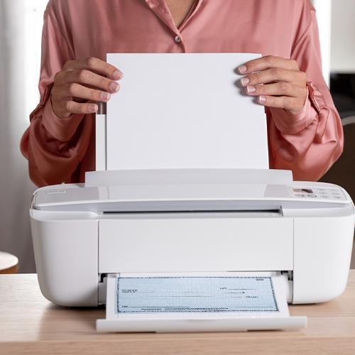 A Woman Holding a Sheet of Paper Checks in Front of a Printer While Checking the Printout