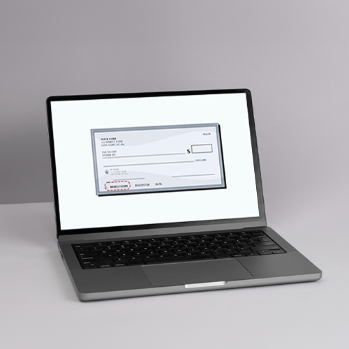 A Laptop with a Check on It on a Table. The Check Shows Bank Check Routing Number