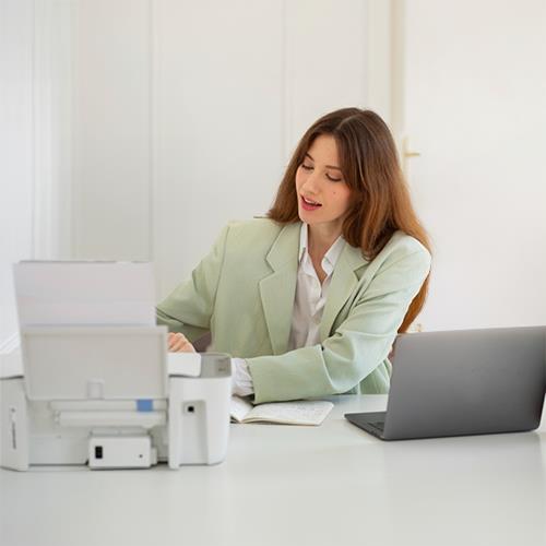 A Woman Managing Her Finances Using a Laptop and Printer to Create Personal Checks Cheapest Rates