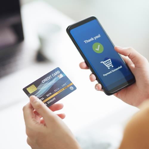 A Woman Holding a Credit Card and a Smartphone, Symbolizing the Best Way To Use A Credit Card To Build Credit.