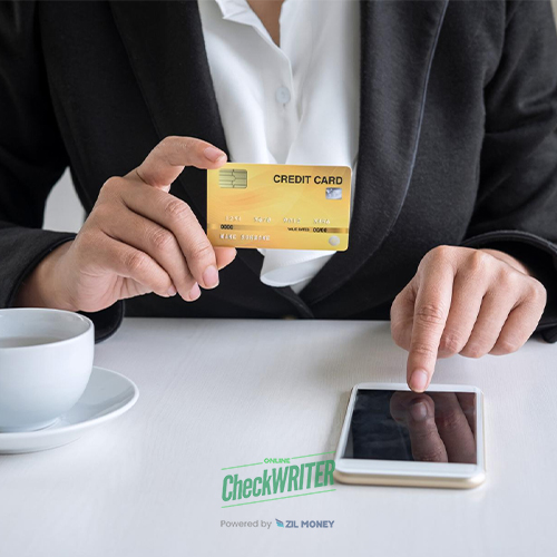 A Business Professional Pay My Mortgage with a Credit Card on a Smartphone and a Coffee Cup Visible on the Desk.