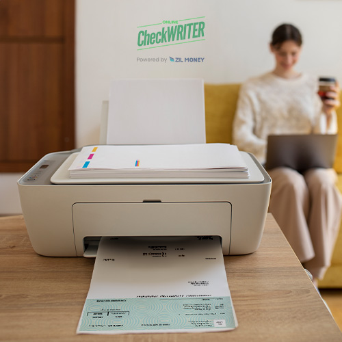 A Modern, Compact Printer on a Wooden Table Printing a Detailed Check, with a Focused Woman in the Background Using a Laptop. That Is Symbolized Costco Checks Personal Alternative