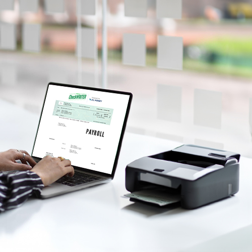 A Person Is Using a Laptop Next to a Printer. The Laptop Screen Displays a Payroll Check Printing. The Printer Has a Partially Printed Check Emerging from It.