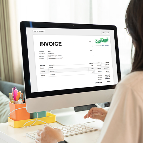 A Person Sits at a Desk Using a Computer. The Computer Screen Displays an Invoice from a Company. Users Can Import Free QuickBooks Invoice.