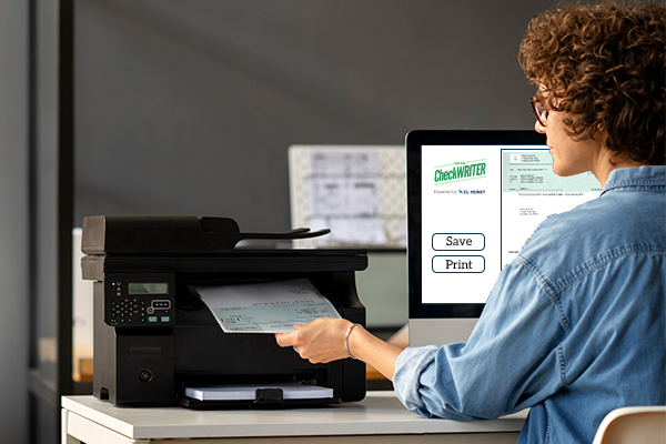 A Person Sits at a Desk Using a Computer and Using a Printer to Print Checks Instead of Personal Check Ordering Online