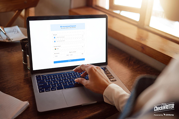 A person uses a laptop to process international payments, highlighting speed and convenience.