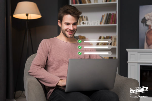 A young man happily works on a laptop, completing tasks with quick checkmarks on the screen, showing payment success.