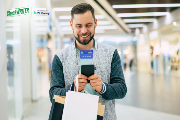 A man shops happily while holding a phone and a virtual card, showing secure and convenient payments.
