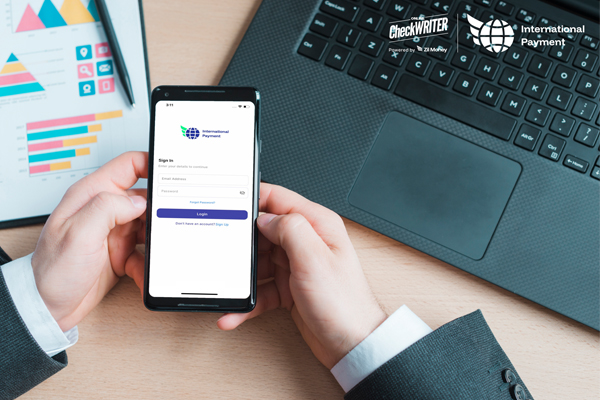 Hands holding a smartphone showing an app sign-in screen for processing international payments easily and securely.