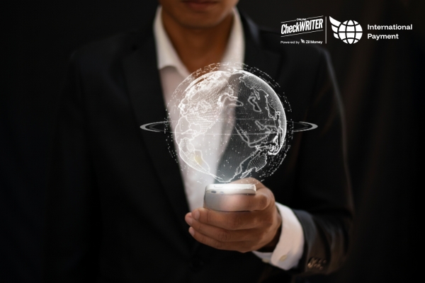 Man in a suit holding a phone that projects a digital globe, symbolizing fast, global international payments.