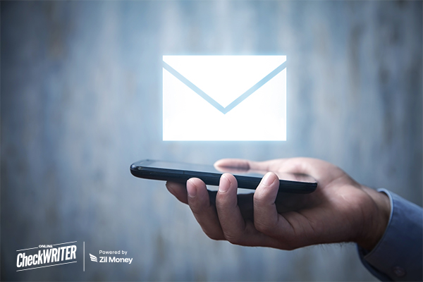 Hand holding a smartphone with a large, glowing envelope icon, symbolizing modern, digital check mailing on the go.