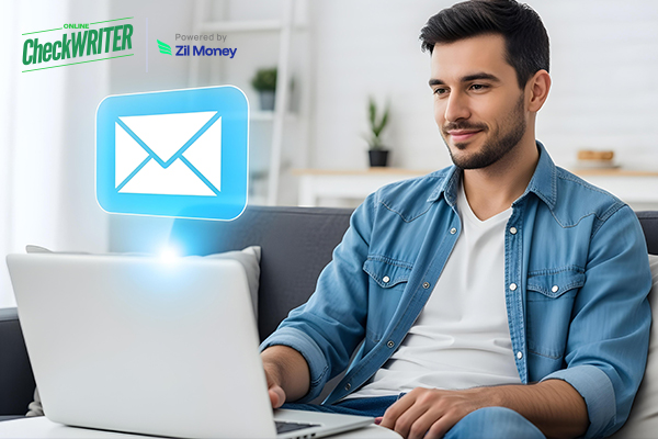 Smiling man on a couch using a laptop with a glowing envelope icon, illustrating digital check mailing convenience.