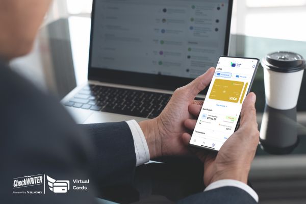 Mission Control How a Virtual Card App Guarantees Smooth Cash Flow for Non-Profits Today Woman's hands hold a smartphone displaying a gold Virtual Card interface for quick expense management on a desk.