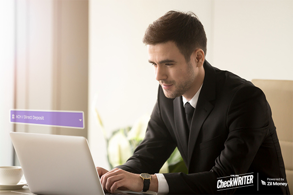 Streamlining Payments: How Direct Deposit is Benefiting Large Corporations Business Professional Using a Laptop to Manage Ach Direct Deposit Payments in a Modern Office Setting.