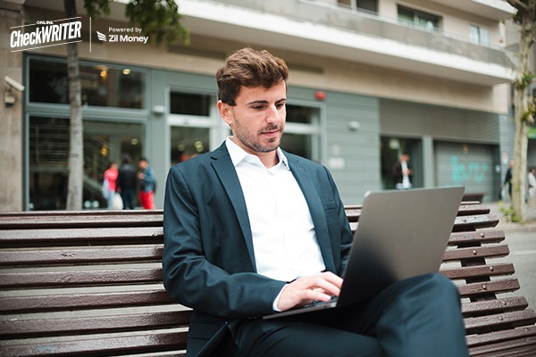 5 Reasons Why Positive Pay Implementation Is Your Best Defense Against Check Fraud in 2026 A businessman using a laptop outdoors, reviewing payments with Positive Pay Implementation for fraud protection.