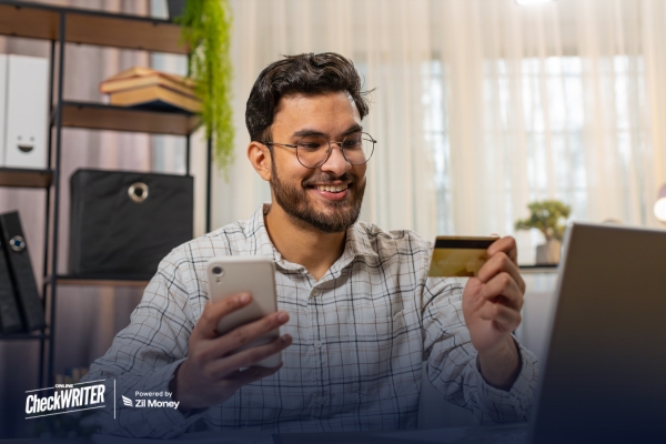 Pay by Credit Card The Smarter Way for Small Businesses to Handle Payments A small business owner using a phone and card at a desk, showing how teams can Pay By Credit Card for quick business payments.