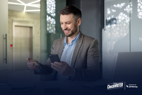 Rent Has Been Your Least Productive Expense – Here’s One Way to Change That Man in a blazer uses his phone to Pay Rent With Any Credit Card, showing a better way to organize expenses.