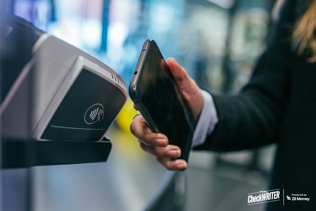 accept a check by phone featured image check mailing by phone - business professional accepting check payment remotely on smartphone