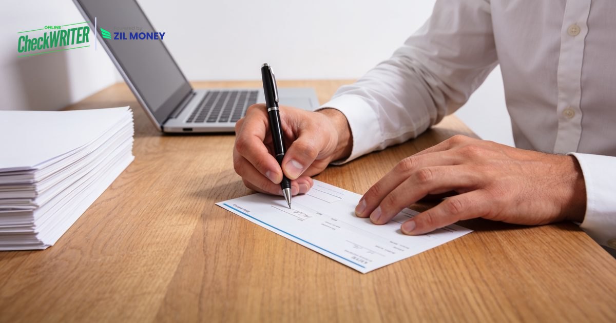 Check Writing With Software at a Desk Check writing at a desk with a pen and laptop using check writing software