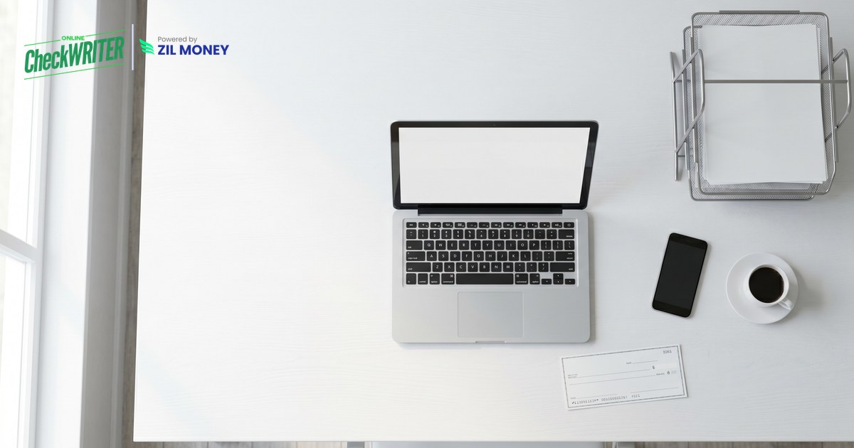 can-you-fax-a-check Clean office desk with a laptop, phone and a paper check illustrating can you fax a check