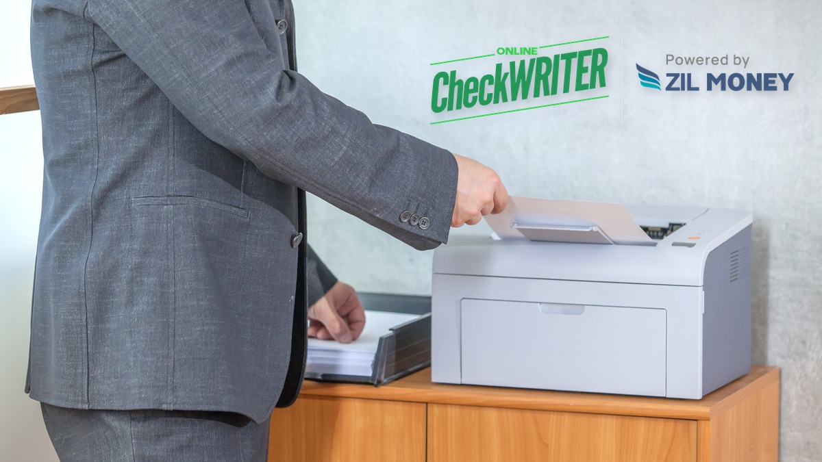 Same Day Checks: Printing a Check at Your Own Desk Hand pulling a freshly printed same day check from a laser printer at an office desk, OnlineCheckWriter.com logo